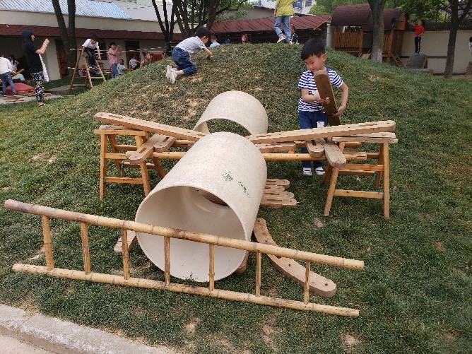 A young boy plays with large tunnels and other makeshift toys