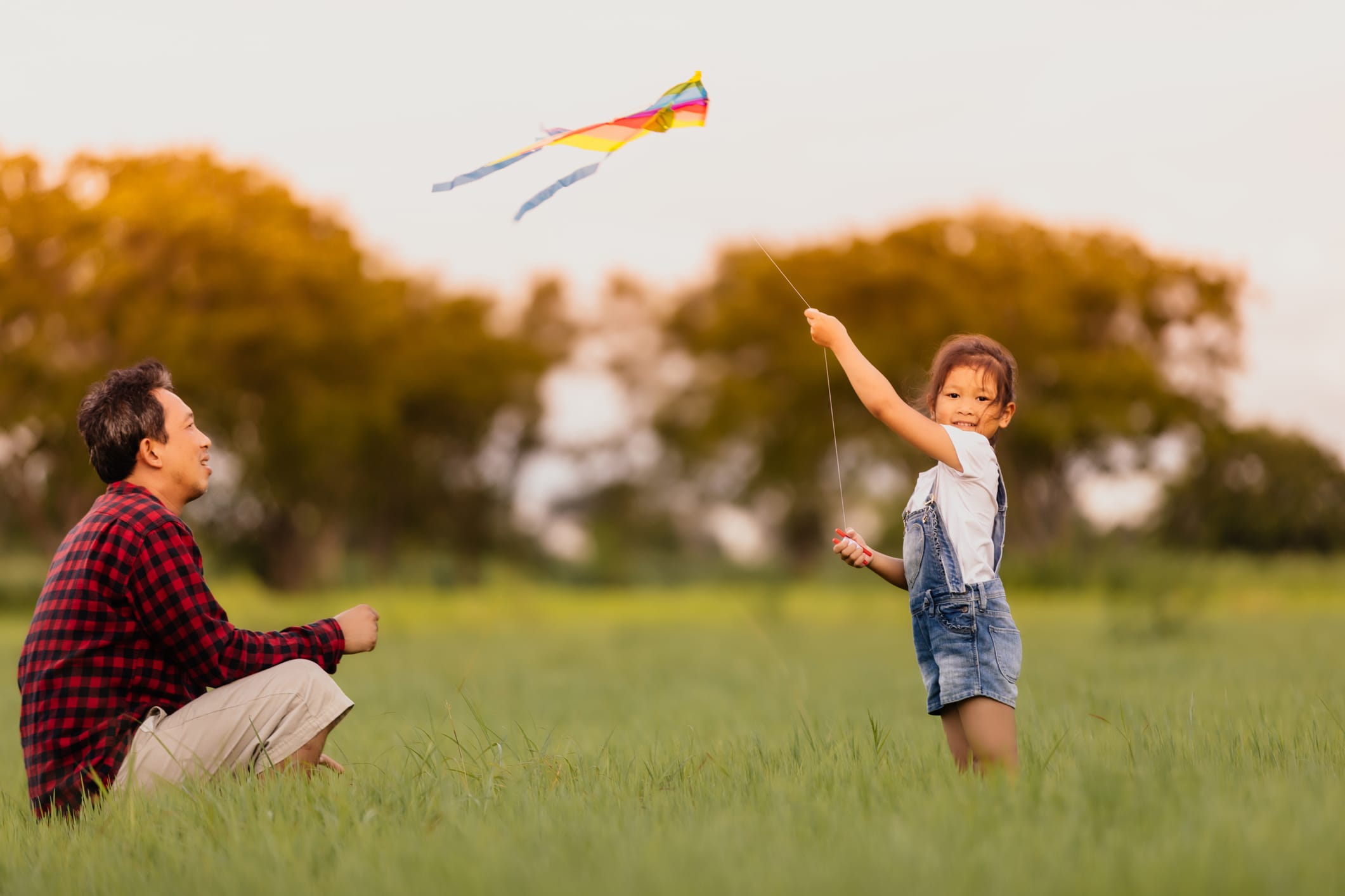 asian girl and dad flying a kite