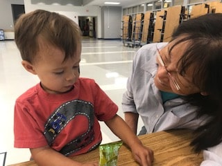 Young child at a table with a smiling grandmother