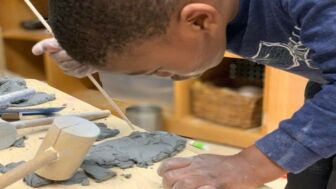 A young black boy crafts with clay