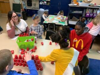 Parents and children smile as they play at a table.