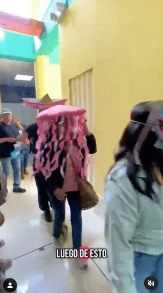 People walk down a hallway, one person wearing a pink jellyfish costume. The caption at the bottom reads "LUEGO DE ESTO.